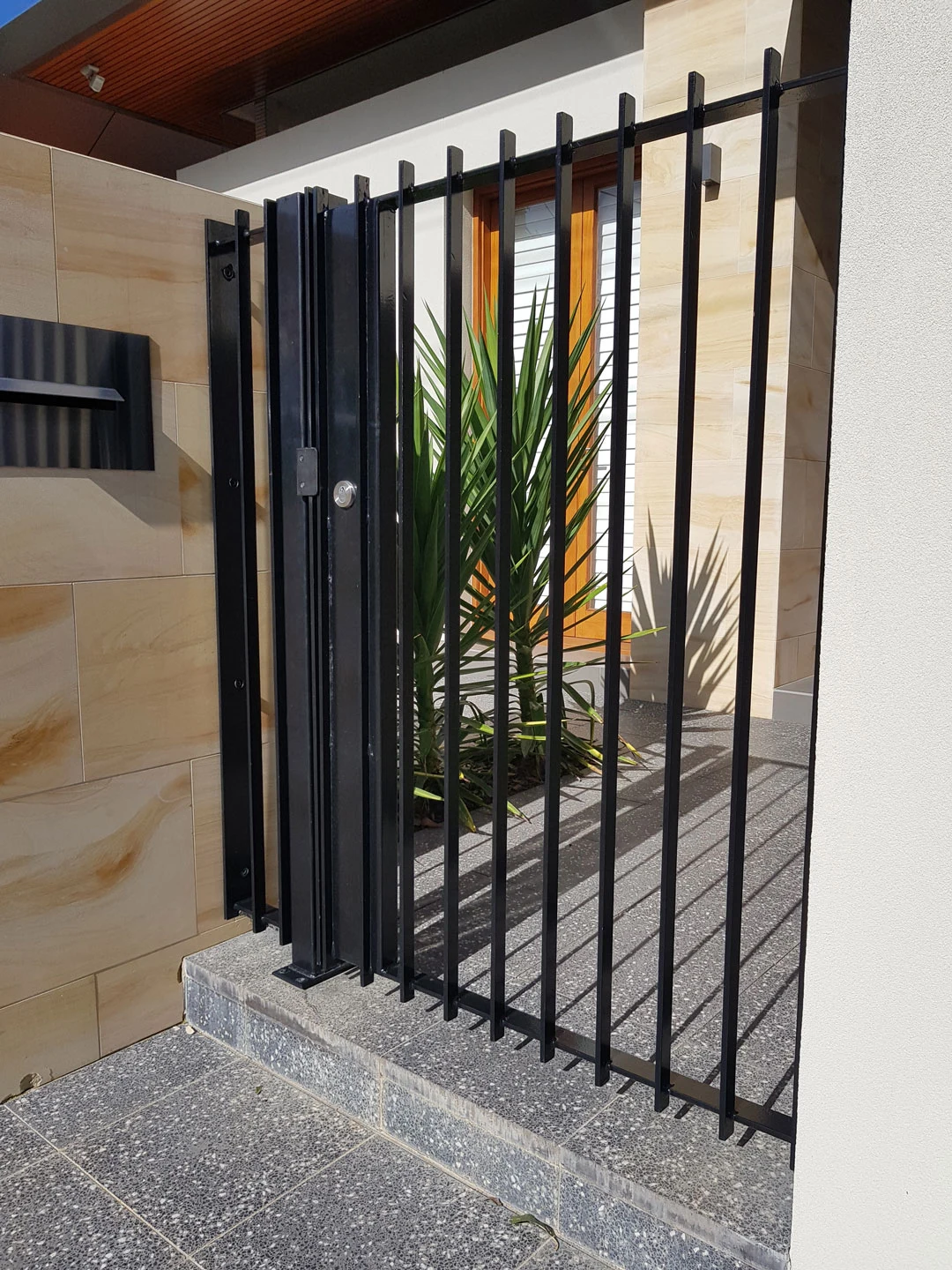 Black steel entry gate installed between stone columns