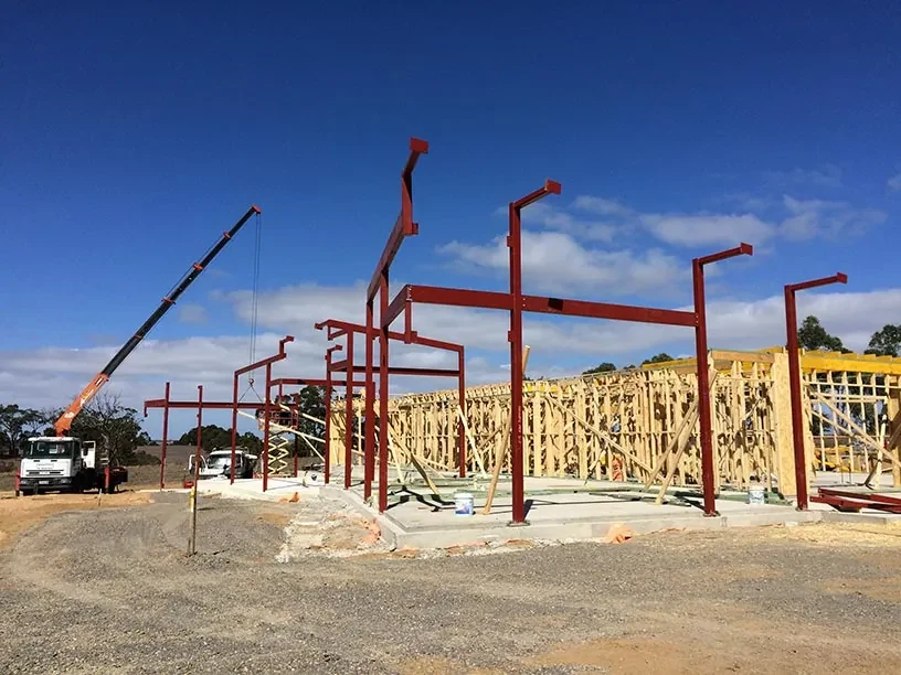 Red structural steel framing installed beside timber framing