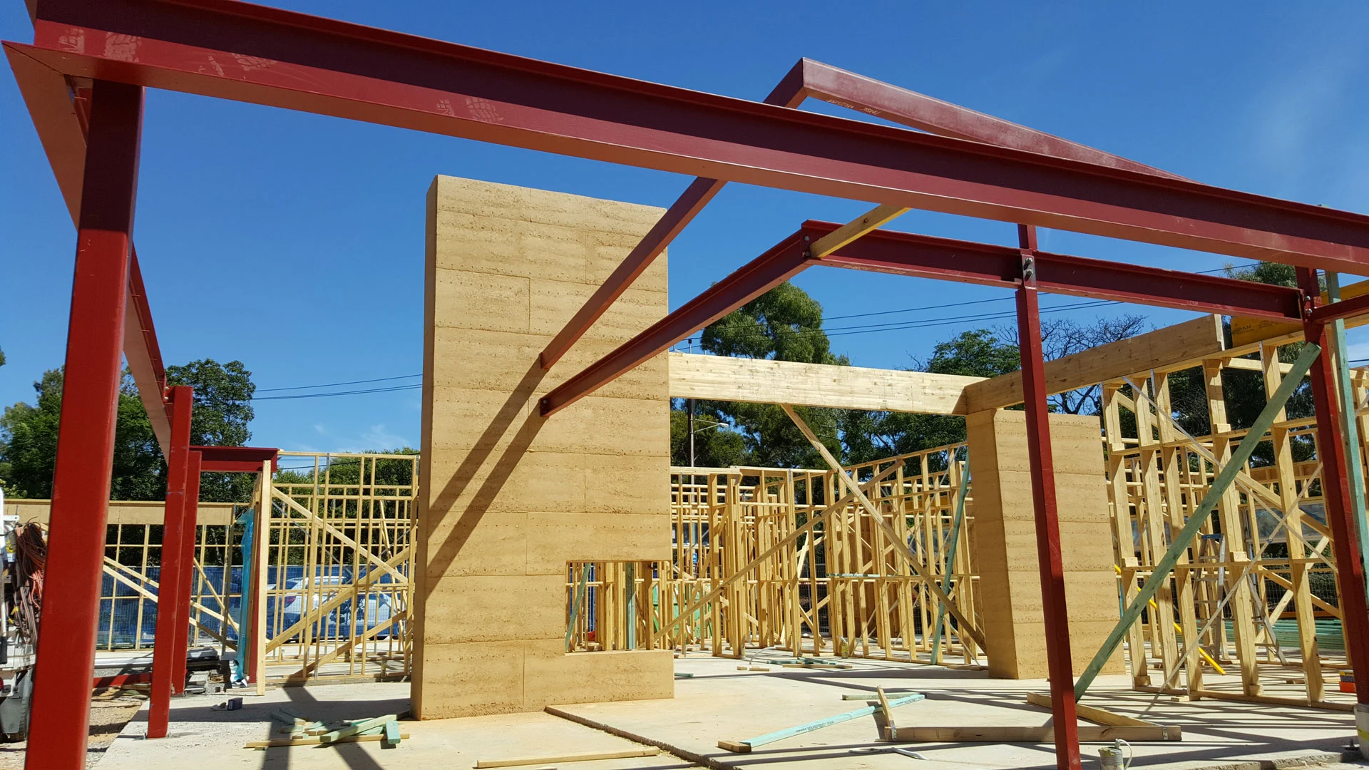 Red steel roof beams installed over a masonry wall