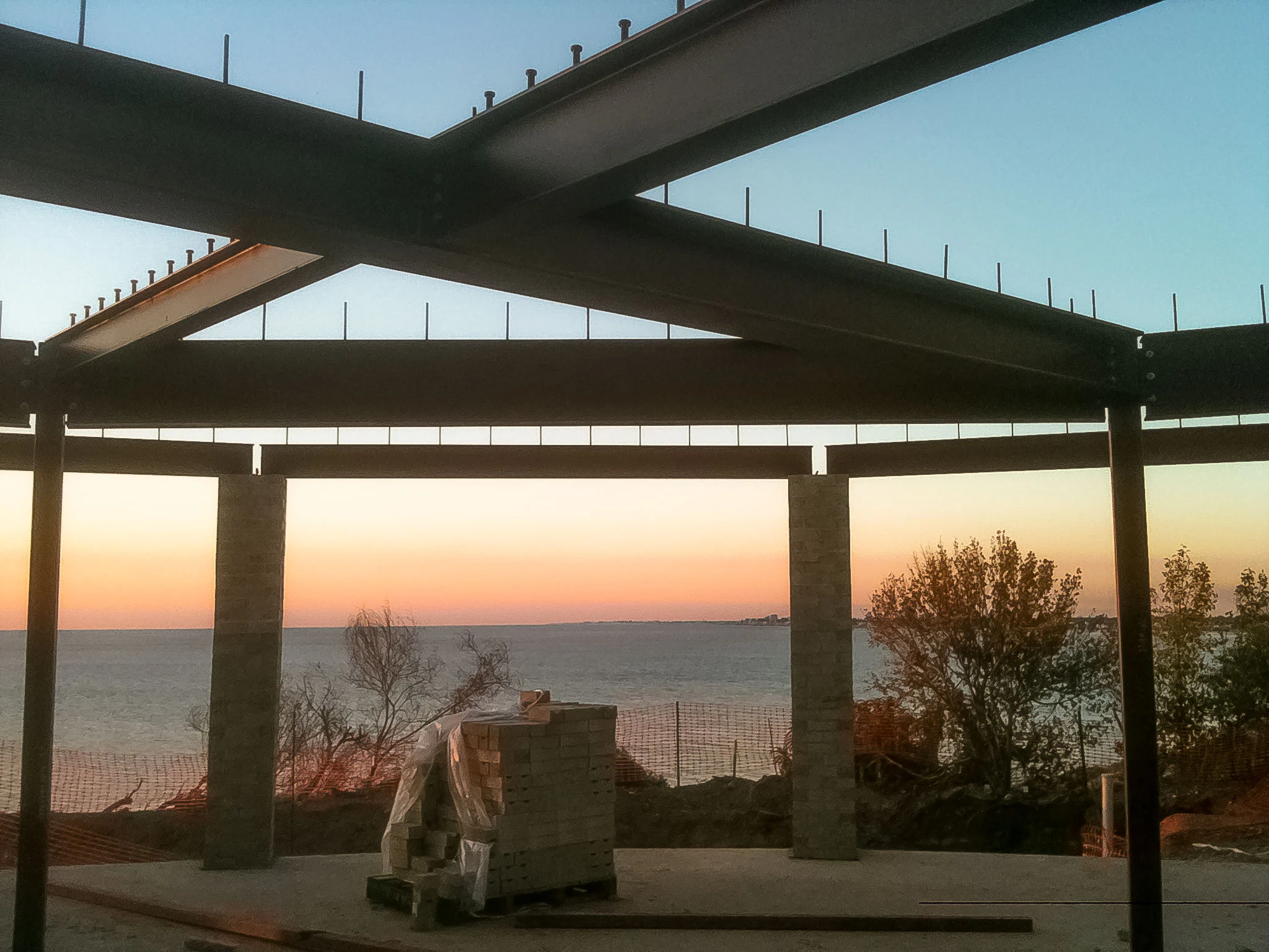 Structural steel roof beams framing the evening sky