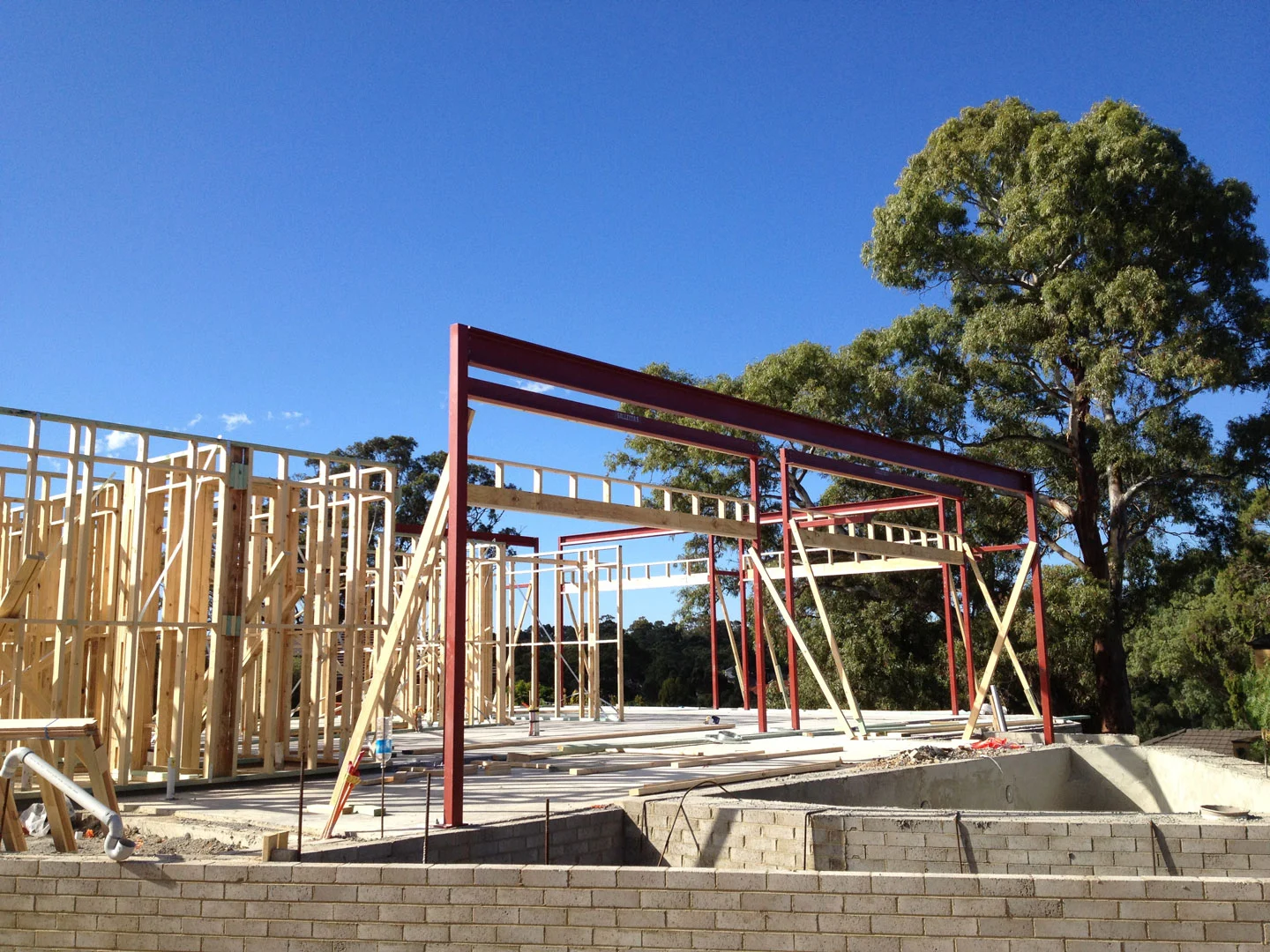 Red structural steel installed around a timber house frame