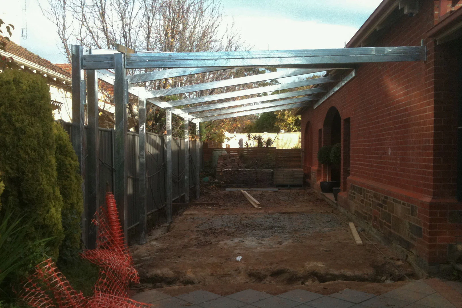 Galvanised steel roof framing beside a brick home