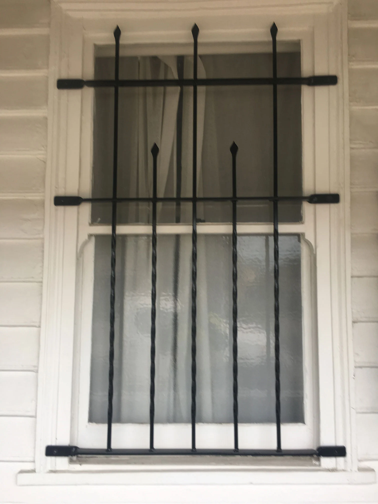 Black spear-top steel security grille over a window